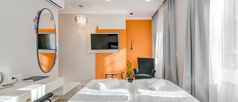 A hotel room with a bed, a desk, a chair, a TV, and a mirror.