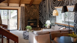 Una sala de estar acogedora con chimenea de piedra, un sofá modular grande y una lámpara moderna.