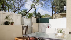 A glass-top table with chairs, a potted plant, and a white wall. - KAV Apartments -Near Assuta Olei Gardom (Tel Aviv)