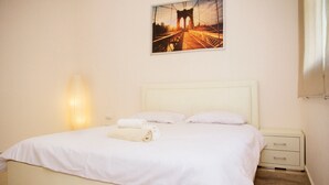 A hotel room with a bed, a nightstand, a lamp, and a painting of a bridge. - KAV Apartments -HaYarkon St. 30 (Tel Aviv)