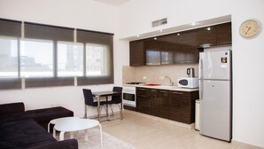 A modern kitchen with a dining area, a refrigerator, a microwave, and a stove. - KAV Apartments -HaYarkon St. 30 (Tel Aviv)