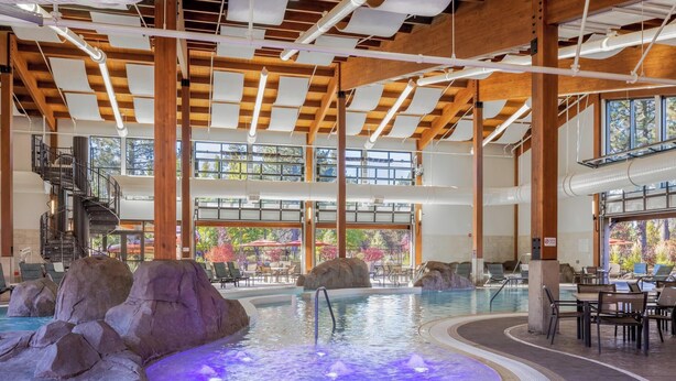 Une piscine intérieure dotée d’un jacuzzi, de formations rocheuses et d’un escalier menant aux niveaux supérieurs.