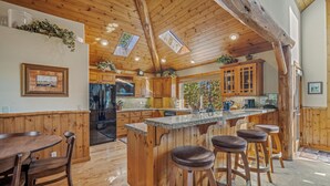 Une cuisine avec des meubles de rangement en bois, un îlot central doté de tabourets et une table à manger.