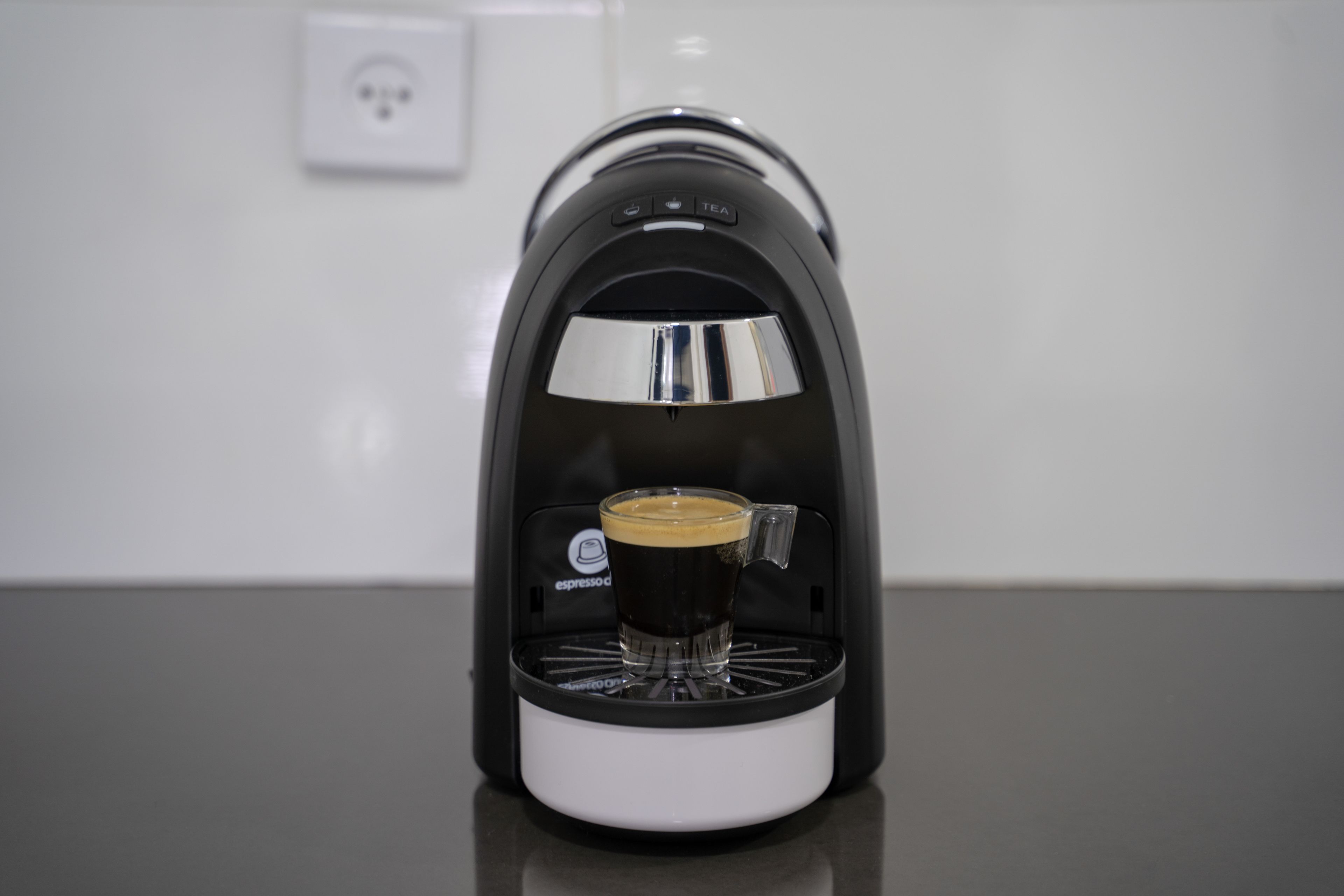 A coffee machine with a cup of coffee being dispensed.