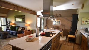 A modern kitchen with a central island, wooden cabinets, and a dining area with chairs. - Family-Friendly Escape with Access to Exclusive Golf (Sunriver)