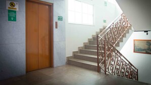 Una escalera con barandillas metálicas ornamentadas, una puerta de madera y un ventanal.