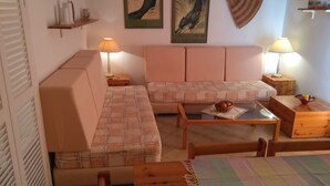 Ein gemütliches Wohnzimmer mit einer Sofagarnitur, einem Couchtisch und einem kleinen Holztisch mit einer Fruchtkorb.