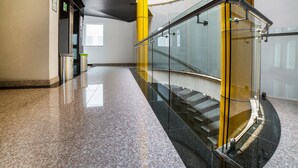 Un intérieur moderne avec une balustrade en verre incurvé, un revêtement de sol en granit poli et un escalier menant à un niveau supérieur.
