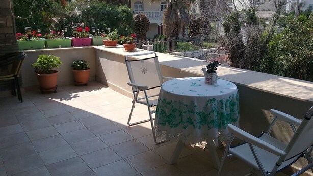 Una terraza con una mesa redonda, sillas y plantas en macetas.