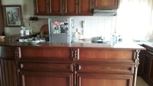 Una cocina con armarios de madera, una isla central y un refrigerador con imanes y notas.