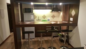 A kitchen with a central island, bar stools, a microwave, and a refrigerator. - Complejo Casas del Mirador (Puimayen)
