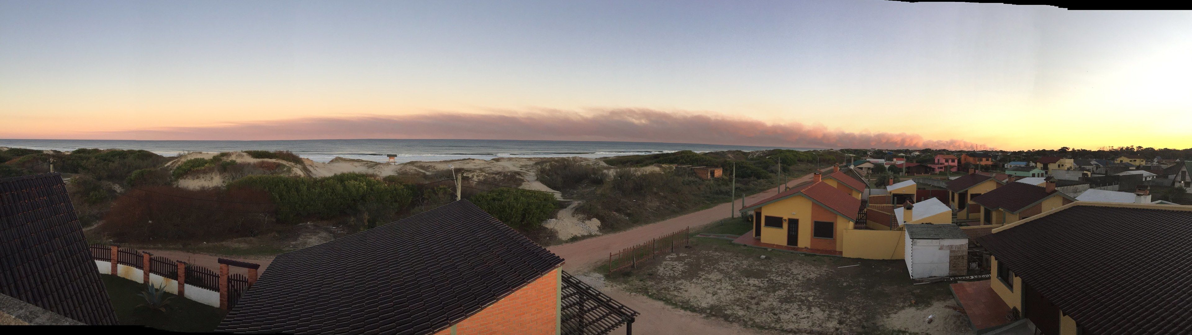 A coastal residential area with houses, a beach, and dunes.