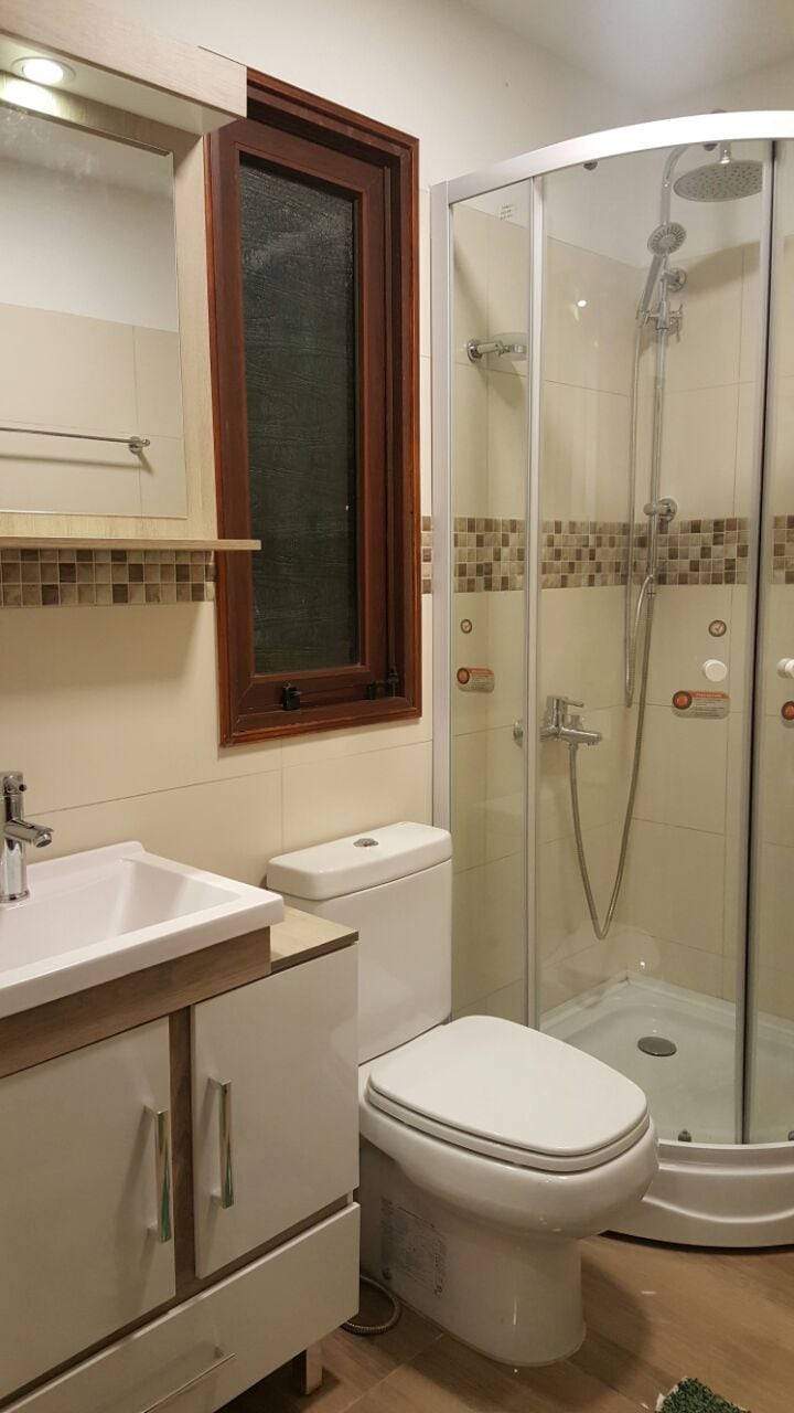 A bathroom with a glass-enclosed shower, a white toilet, and a vanity with drawers.