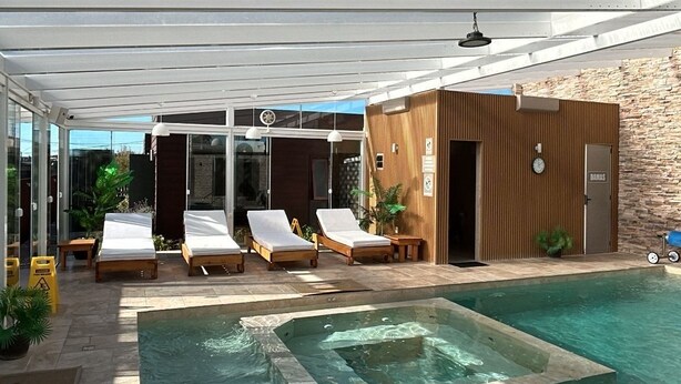 A pool area with lounge chairs, a hot tub, and a wooden cabin. - Complejo Casas del Mirador (Puimayen)