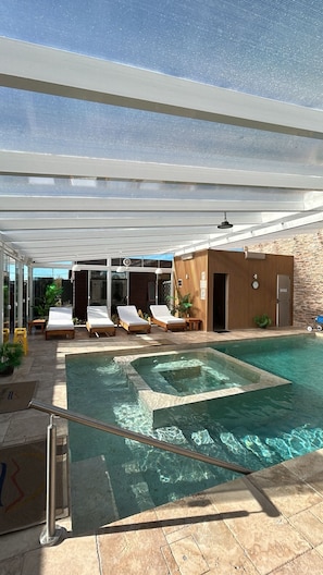 A pool area with lounge chairs, a hot tub, and a wooden cabin. - Complejo Casas del Mirador (Puimayen)