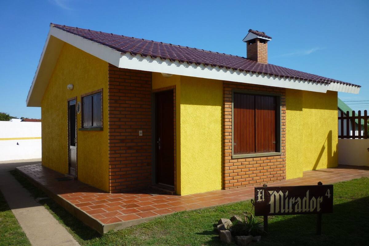 A small yellow building with a red-tiled roof and a brick facade.