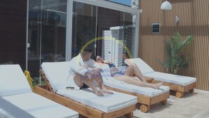 Three sun loungers with white cushions, a wooden deck, and a glass door leading to a building with vertical wooden siding. - Complejo Casas del Mirador (Puimayen)