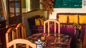 Un comedor con una mesa cubierta por un mantel floral, rodeado de sillas de madera.