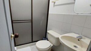 A small bathroom with a toilet, sink, and a shower area. - Hotel Empresarial  (Pereira)