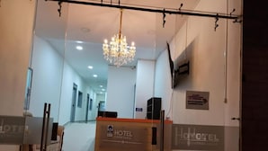 A hotel reception area with a chandelier, a reception desk, and a sign indicating the hotel name. - Hotel Empresarial  (Pereira)