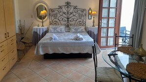Une chambre à coucher comprenant un lit, deux tables de chevet, une armoire, une table en verre et une vue sur l’extérieur.