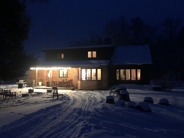 A log cabin with a porch, outdoor seating, and a snow-covered yard. - Quiet, isolated, beautiful home (Crivitz)