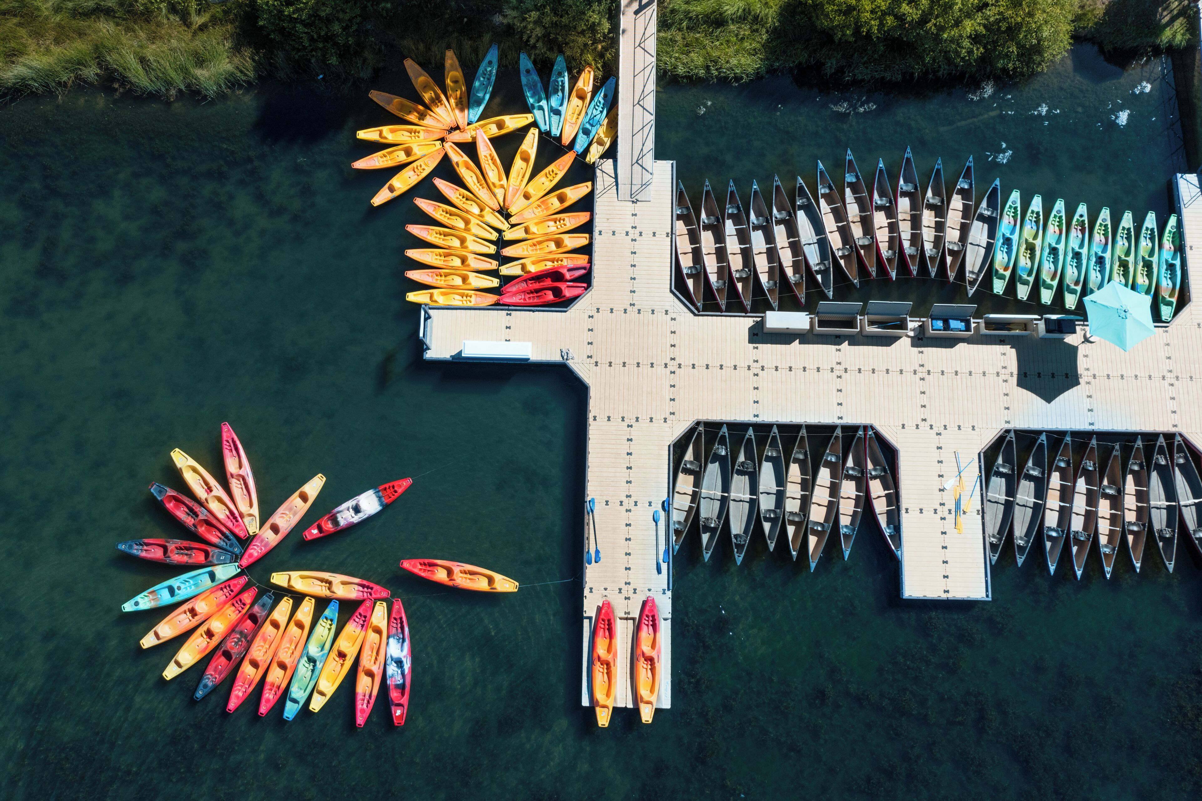 Vue aérienne d’un quai où de nombreux canoës et kayaks sont alignés en rangées.