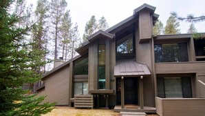 A modern multi-story house with large windows and a covered entryway.