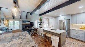 A modern kitchen with a central island, stainless steel appliances, and a dining area with a marble table.
