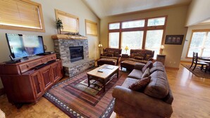 A living room with a fireplace, a television, a sofa, and a coffee table. - Family Retreat with Access to The Cove (Sunriver)