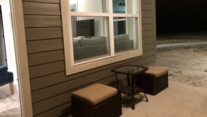 Ein Zimmer mit großem Fenster, einem kleinen Tisch und zwei gepolsterten Sitzgelegenheiten.