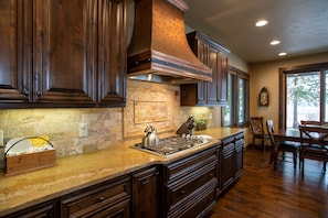 Enjoy meals in this kitchen with a central island, brick backsplash, and dining area with a wooden table.