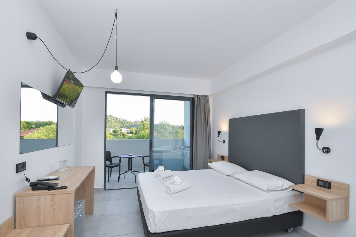 Une chambre d’hôtel moderne équipée d’un lit, d’un bureau et d’un balcon avec vue.
