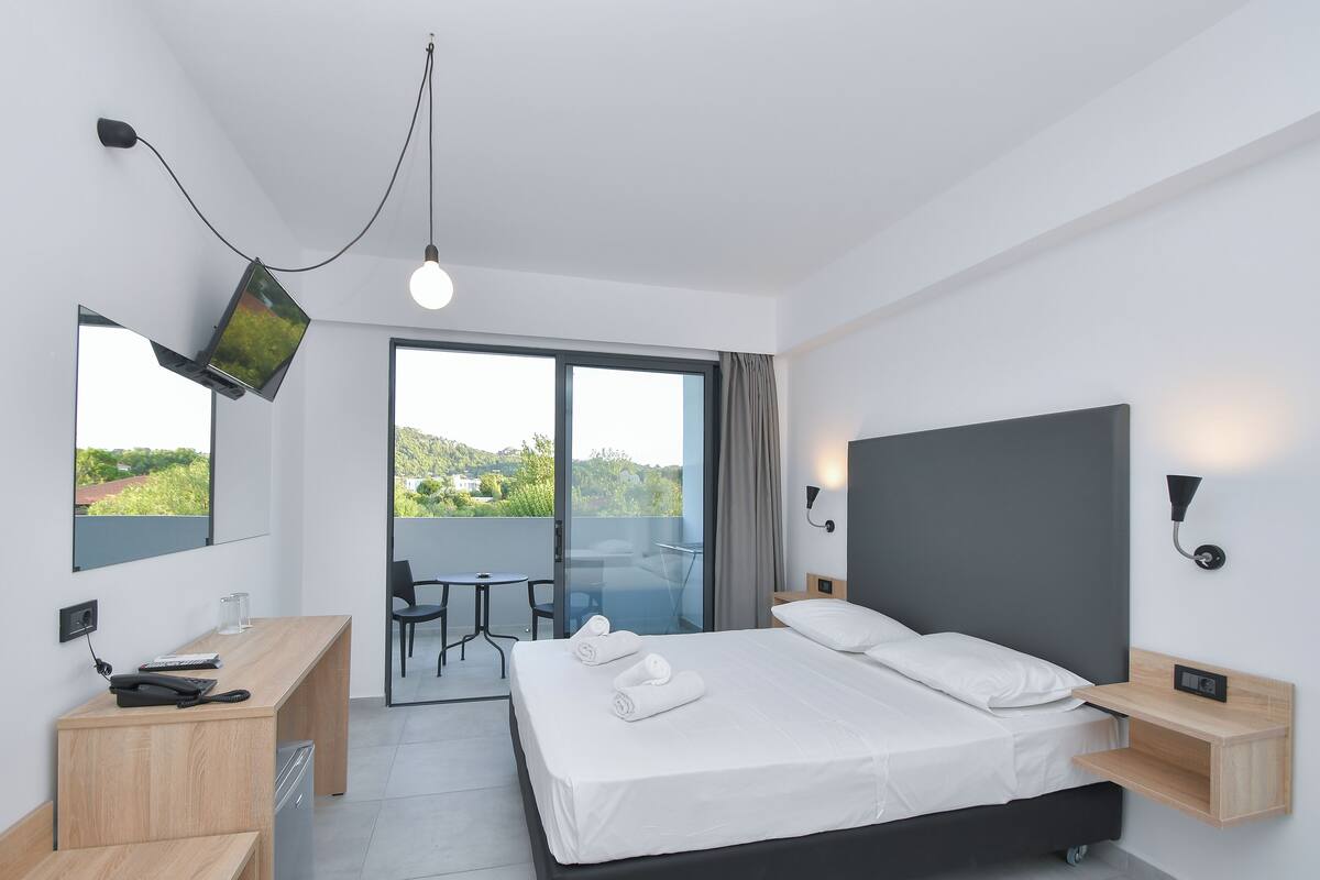 Une chambre d’hôtel moderne équipée d’un lit, d’un bureau et d’un balcon avec vue.
