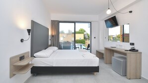 Une chambre d’hôtel moderne équipée d’un lit, d’un bureau et d’une télévision.