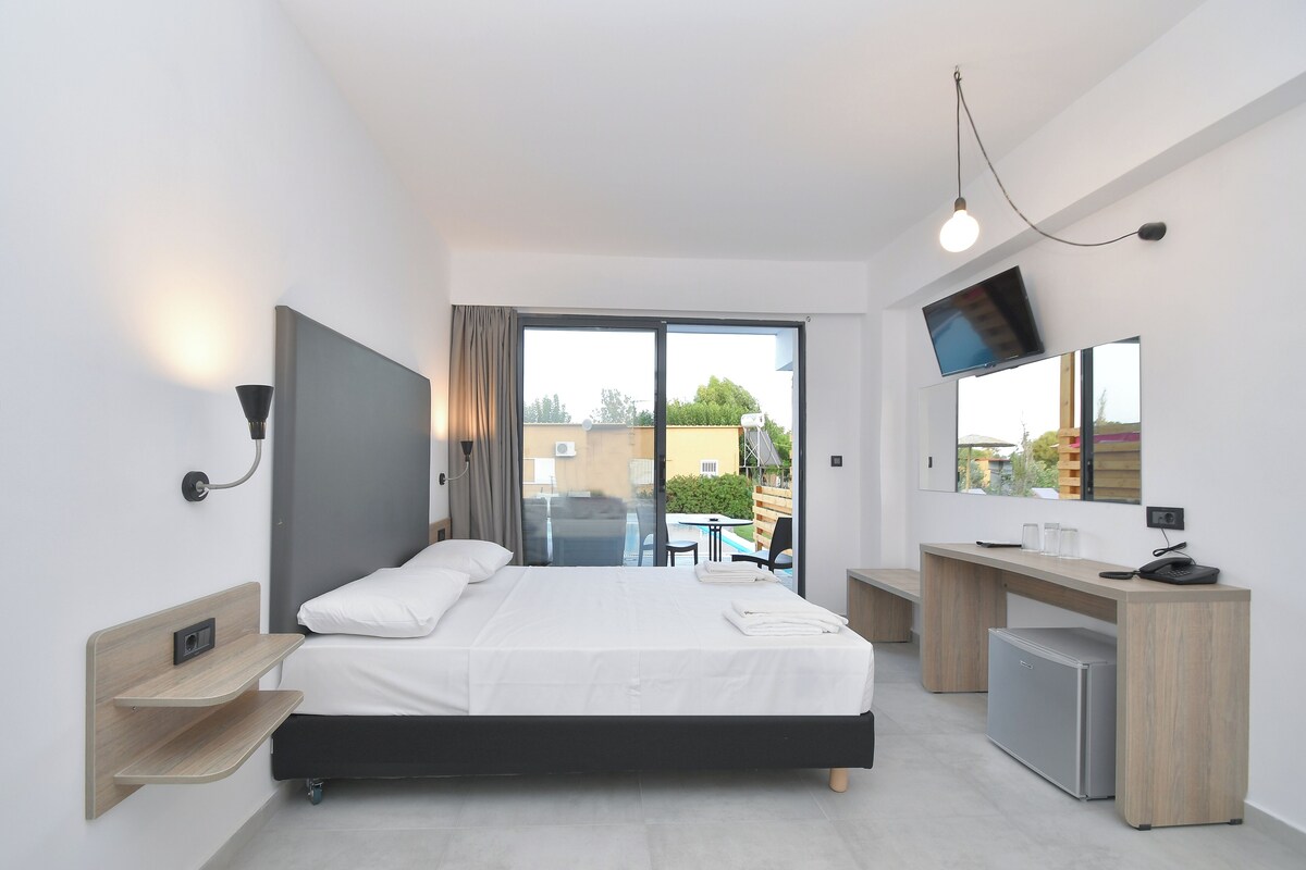 A modern hotel room with a bed, desk, and TV.