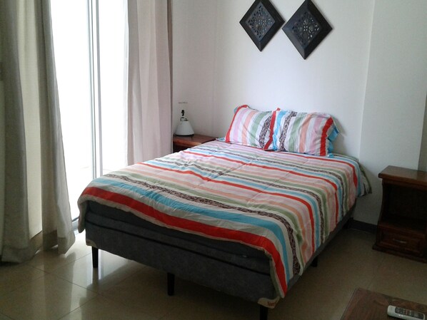A neatly arranged bedroom with a bed, a bedside table, a lamp, and two wall-mounted decorative items.