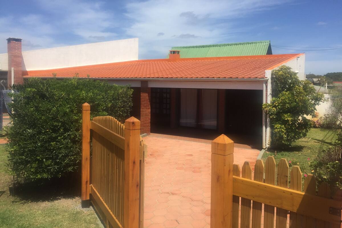Une maison avec un toit recouvert de tuiles rouges, une cheminée en briques et un portail en bois.