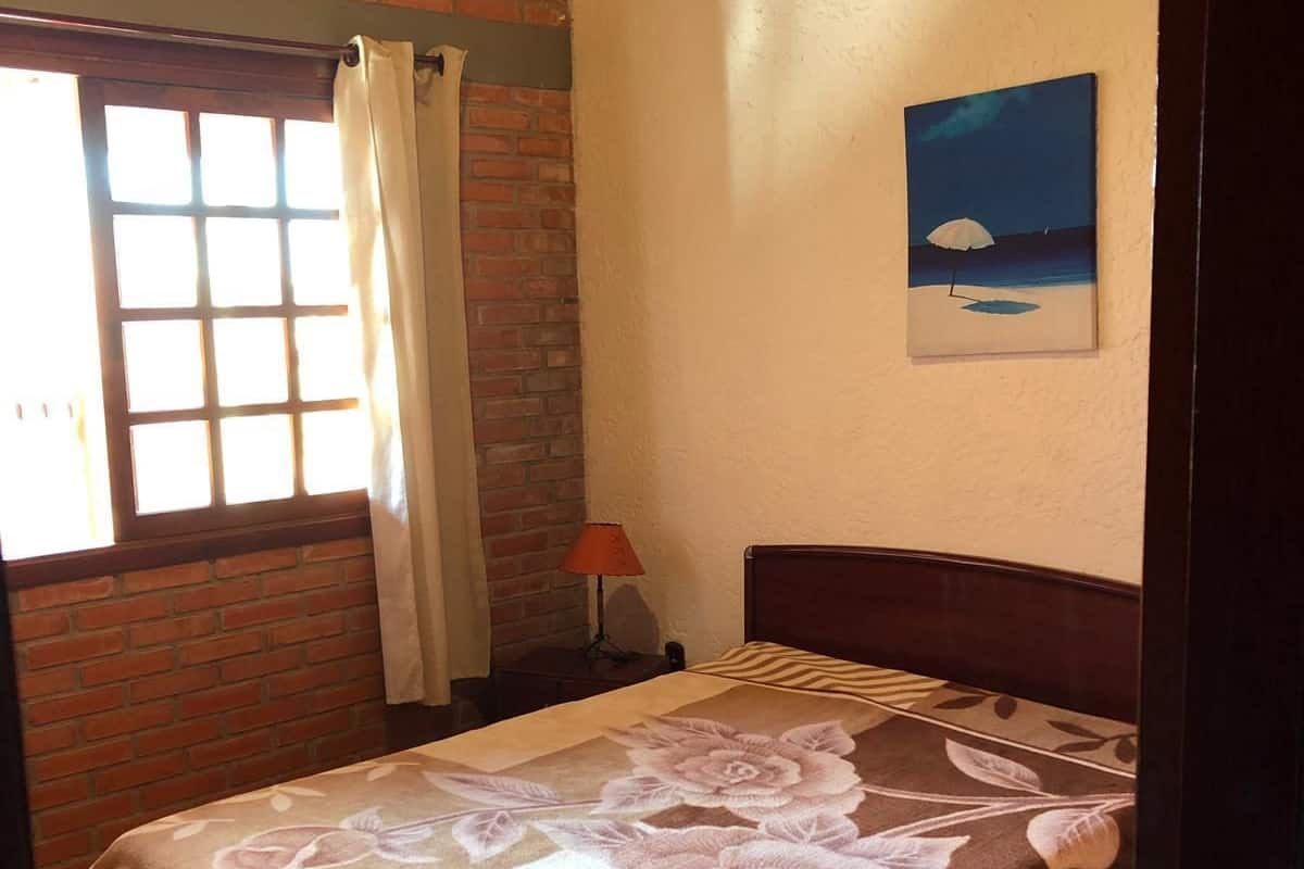 Une chambre à coucher avec un lit, une fenêtre avec des rideaux, une lampe et un tableau au mur.