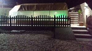 A tent-like structure with a wooden fence, a staircase, and a potted plant.
