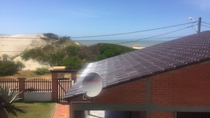 A house with a satellite dish, a brick roof, and a view of the beach.