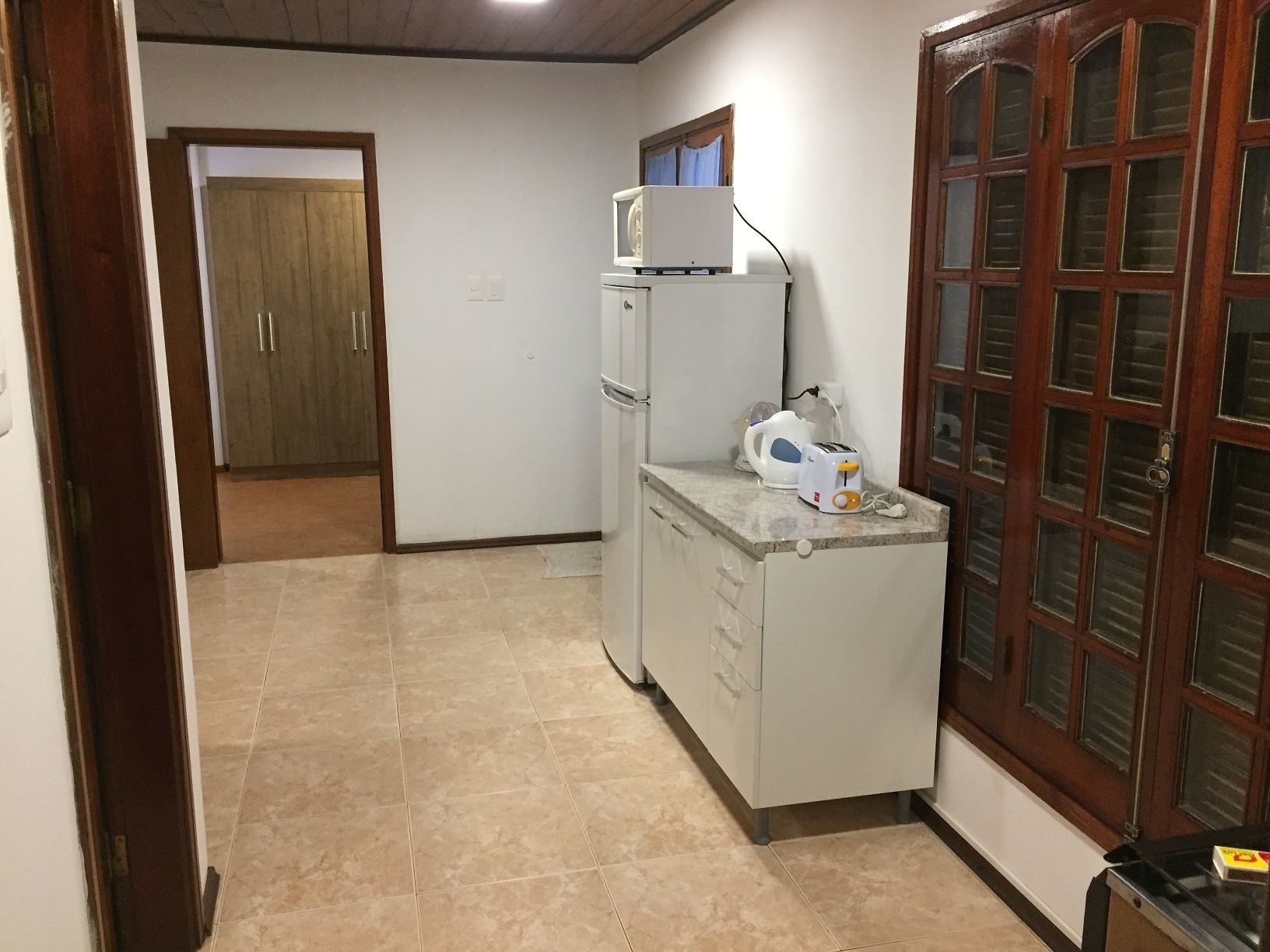 Cocina compacta con refrigerador, microondas y tostadora sobre la encimera.