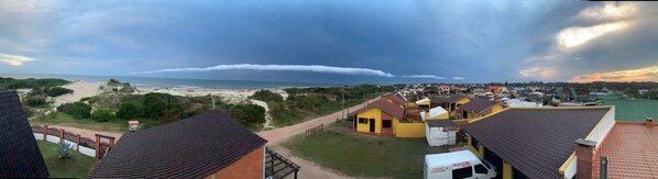 A coastal town with a beach, houses, and a cloudy sky.