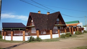 A house with a unique triangular roof and a fenced yard.