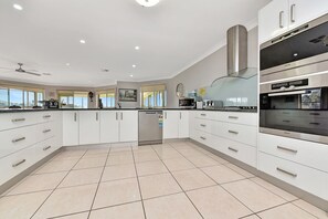 A modern kitchen with white cabinetry, stainless steel appliances, and a tiled floor.