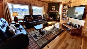 A cozy living room with a leather sofa, a coffee table, a fireplace, and a bookshelf. - Mountain Oasis Luxurious w/ 5 Star Amenities! (Bryson City)