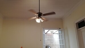 Ein Zimmer mit Deckenventilator, einem Fenster mit Blick und einer Tür.