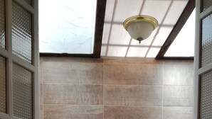 Ein Badezimmer mit einem runden Spiegel, einem Waschbecken mit weißer Arbeitsplatte und einem Fliesenboden.
