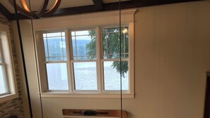 Una habitación con un ventanal grande que da a una masa de agua, chimenea y un letrero que dice "LAKE".