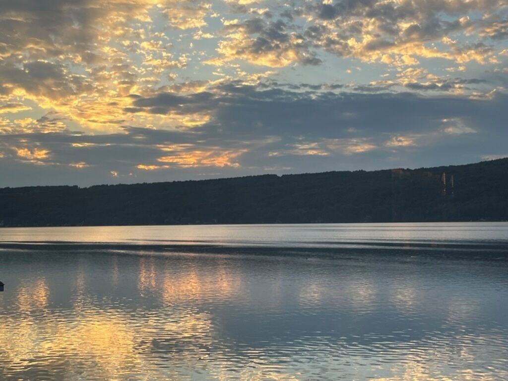 En stilla sjö som speglar himlen, omgiven av ett skogsområde.